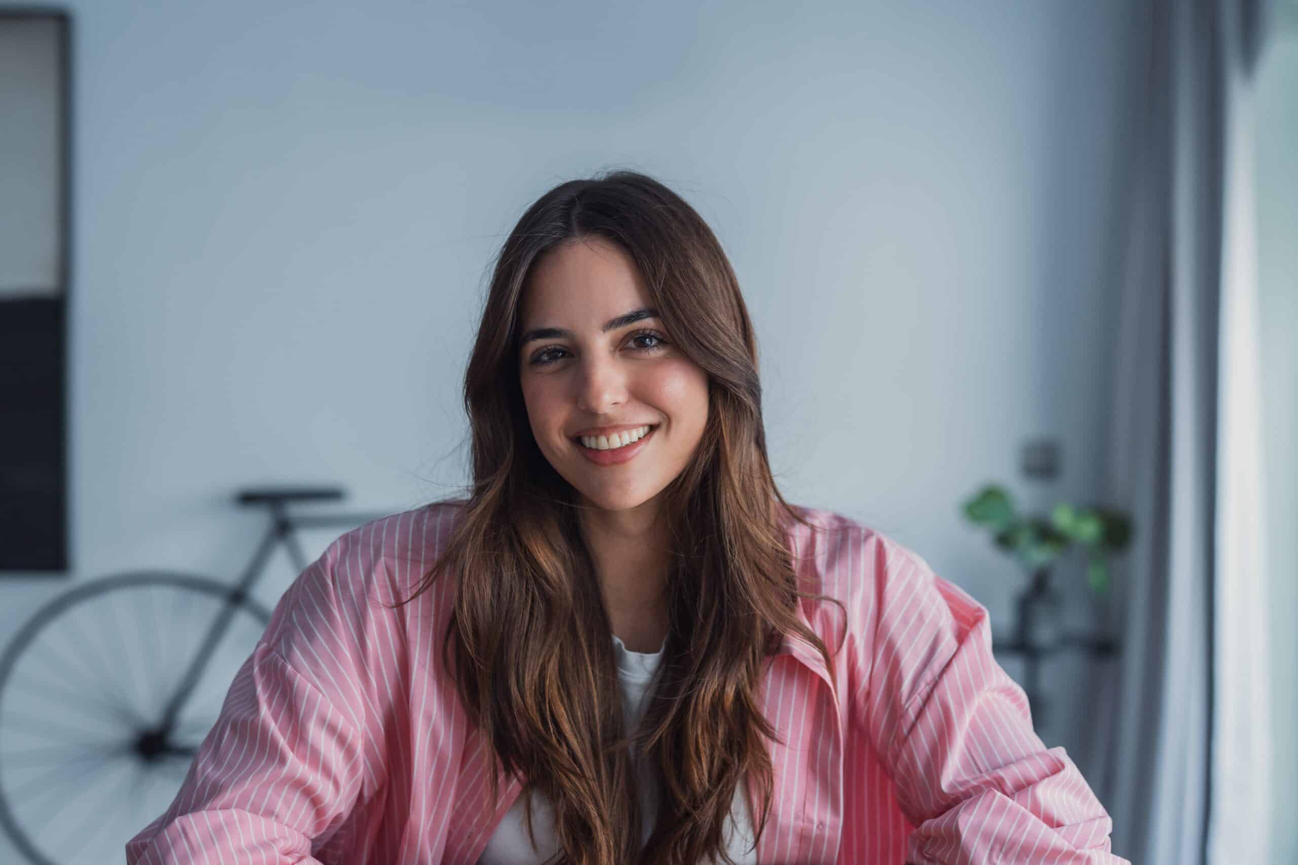 Smiling,Woman,Wearing,A,Pink,Shirt,And,Long,Hair,Sits