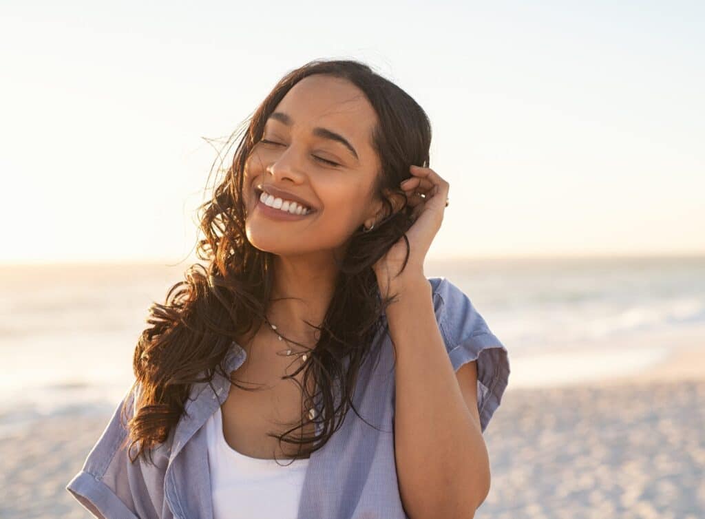 Smiling,Latin,Hispanic,Woman,Relaxing,On,Beach,With,Closed,Eyes